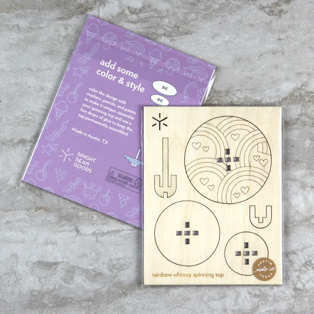 Flatpacked package of wooden craft kit to make your own spinning top with rainbows and hearts on it. 