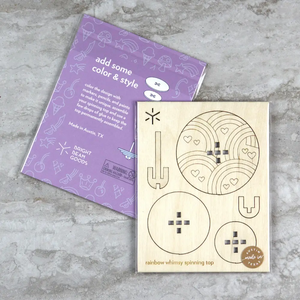 Flatpacked package of wooden craft kit to make your own spinning top with rainbows and hearts on it. 