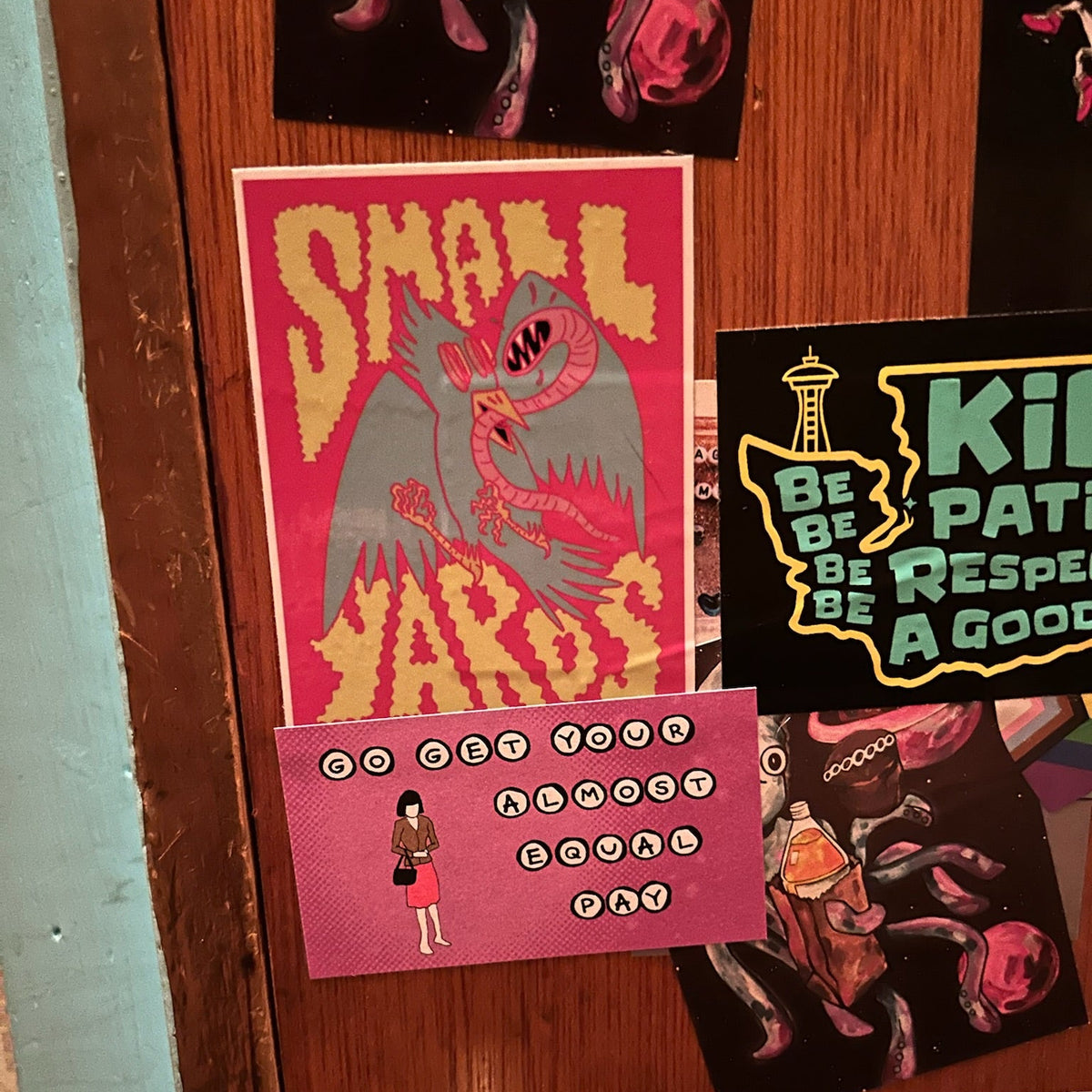 A collection of colorful graphic stickers displayed on a brown wooden door.