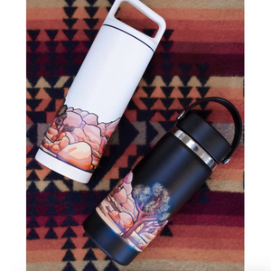 Two insulated travel mugs with Joshua Tree themed designs on a patterned fabric background