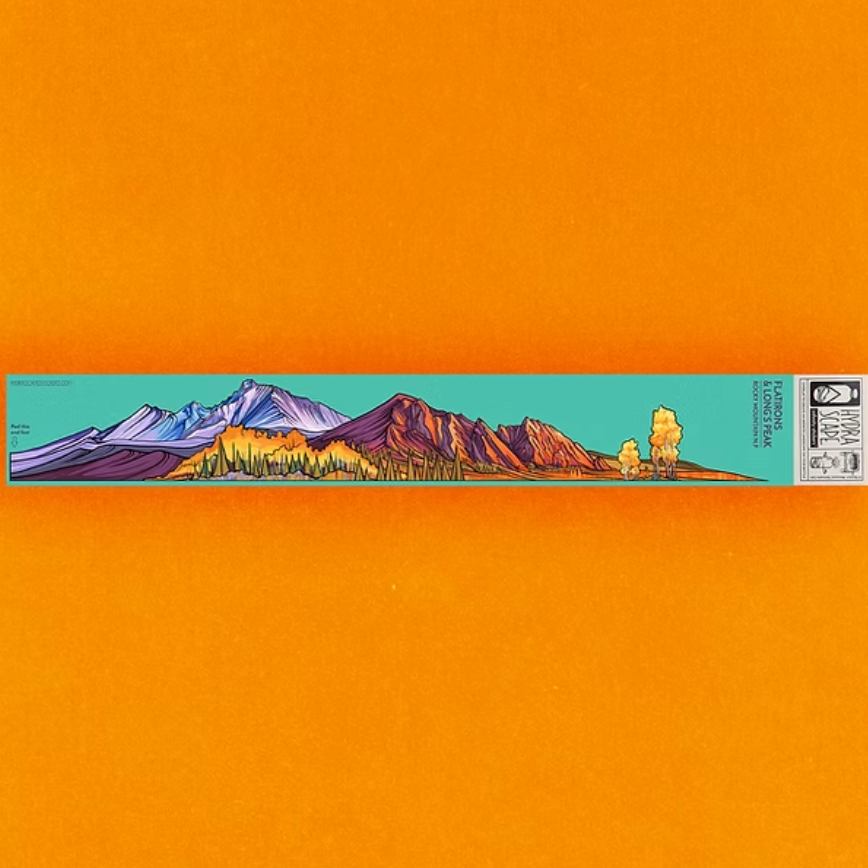 Colorful mountain landscape design on a turquoise strip with a black and white label against an orange background