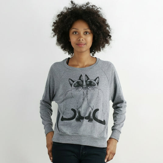 Person wearing a gray sweatshirt with cat design on a plain background.