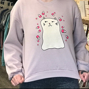 Person wearing a blush pink sweatshirt with a ghost kitty design in a store setting. 