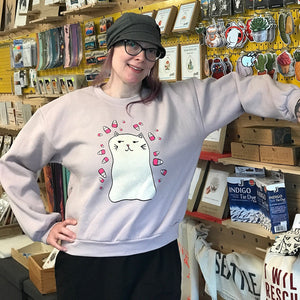 Person wearing a sweatshirt with a cat graphic in a store setting. 