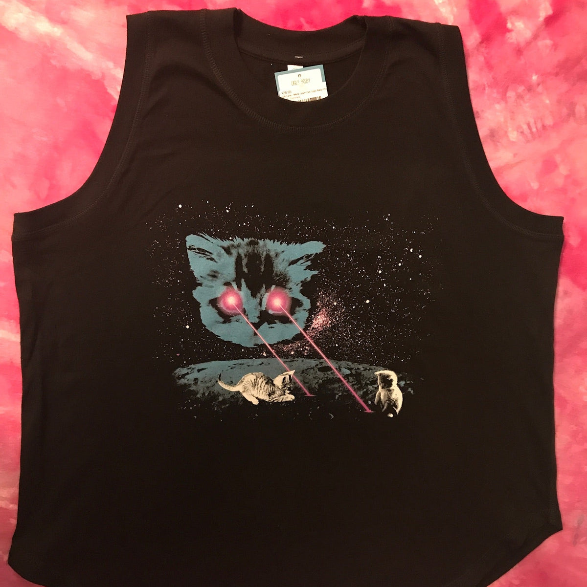 Black sleeveless tank top with Meta Laser Cat design on the front is laid flat on a  pink tie dye background.