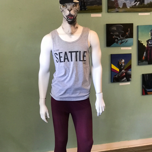 Mannequin wearing a 'Seattle' tank top in front of a wall with framed pictures.
