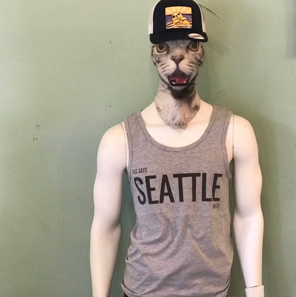 Mannequin wearing a 'Seattle' tank top and a cap with a cat head mask against a plain background