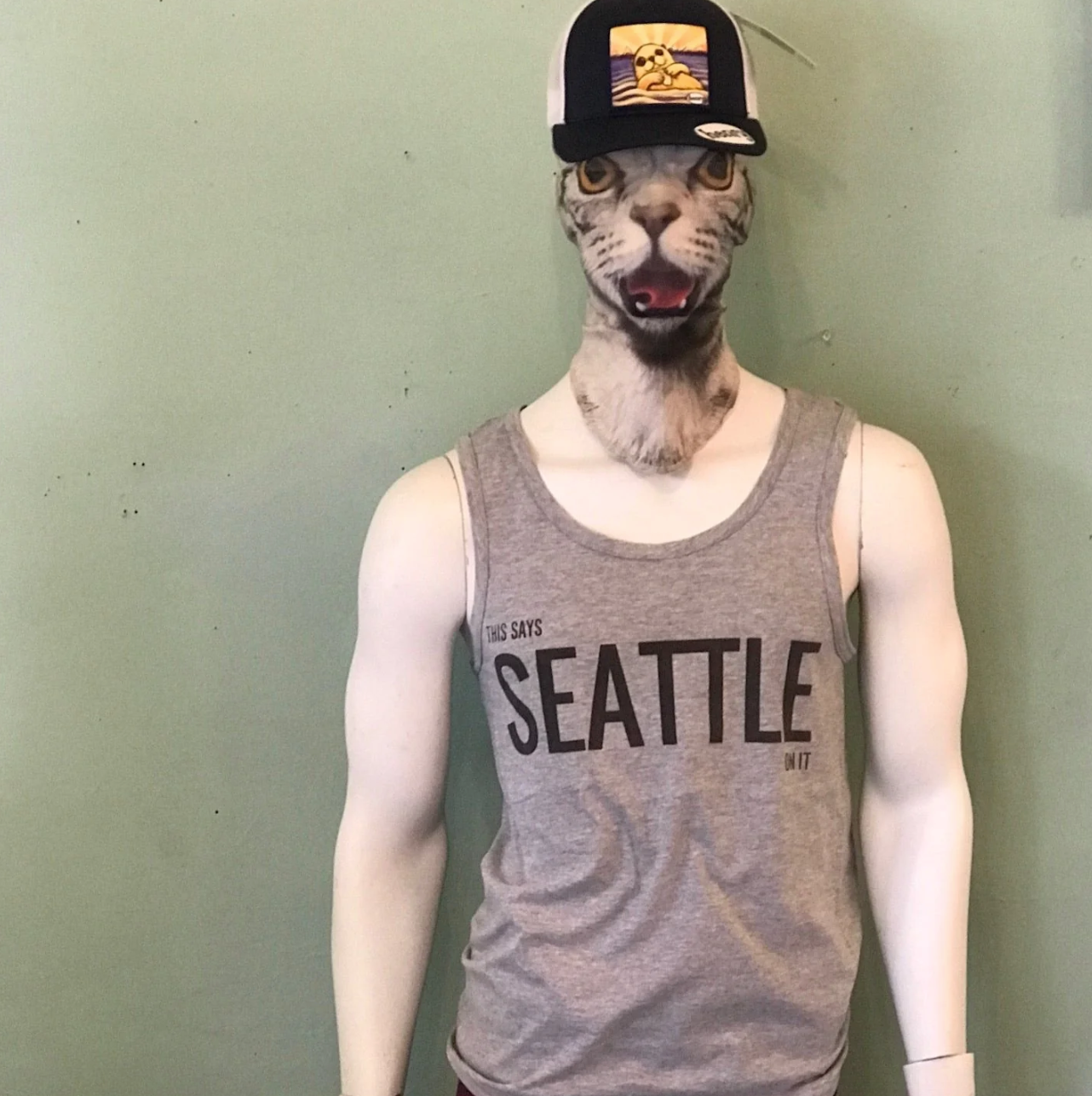 Mannequin wearing a 'Seattle' tank top and a cap with a cat head mask against a plain background