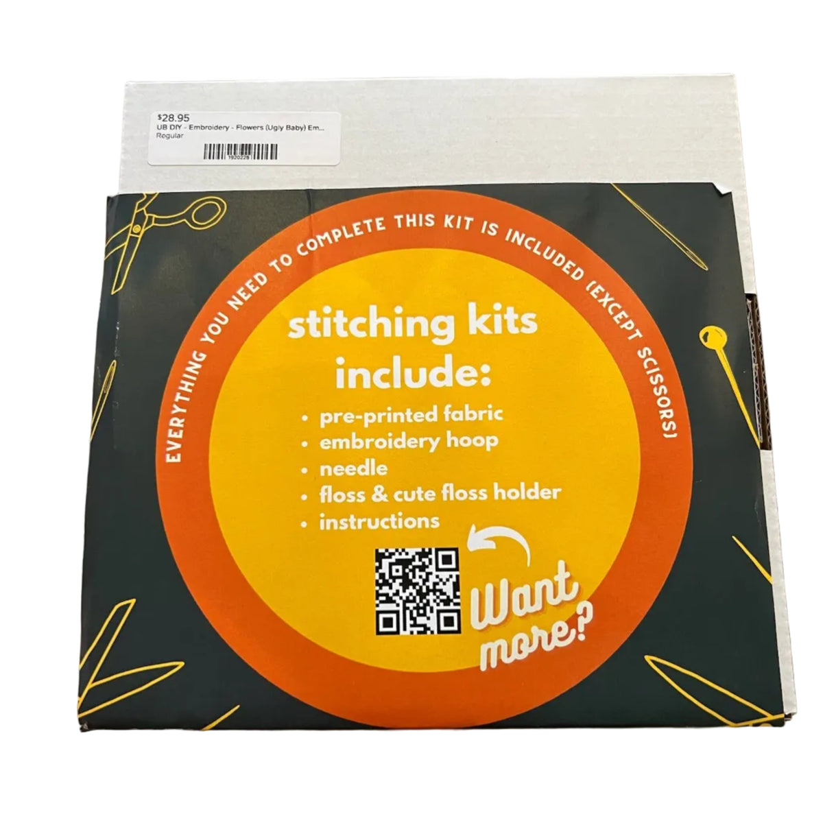 A square product box for an embroidery kit, photographed from above on a wooden surface. The box is dark forest green with a large orange circular label reading 'stitching kits include:' and listing contents such as pre-printed fabric, embroidery hoop, needle, and instructions.