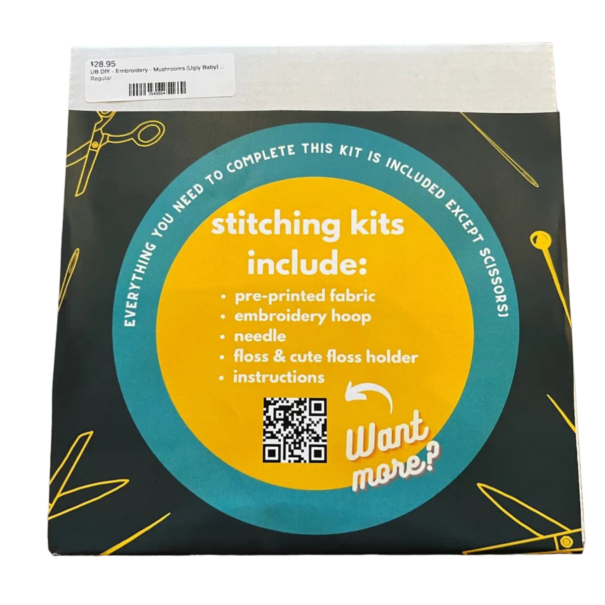 A square product box for an embroidery kit. The box has a dark forest freen background with a large yellow circular label and teal accents, plus small yellow line drawings of scissors and sewing tools.