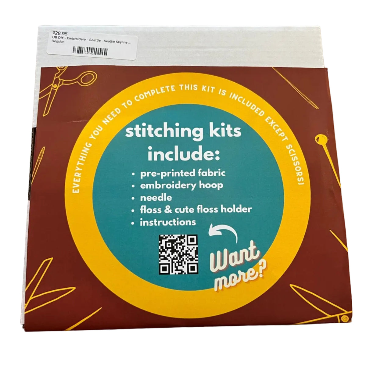 A square product box for an embroidery kit. The box has a dark red background with a large teal and yellow circular label reading 'stitching kits include:' and listing items such as pre-printed fabric, embroidery hoop, needle, floss, and instructions.
