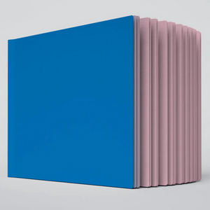 A close up photo of the Pluto ugly book sketchbook. The cover is blue and the pages are light pink colored.
