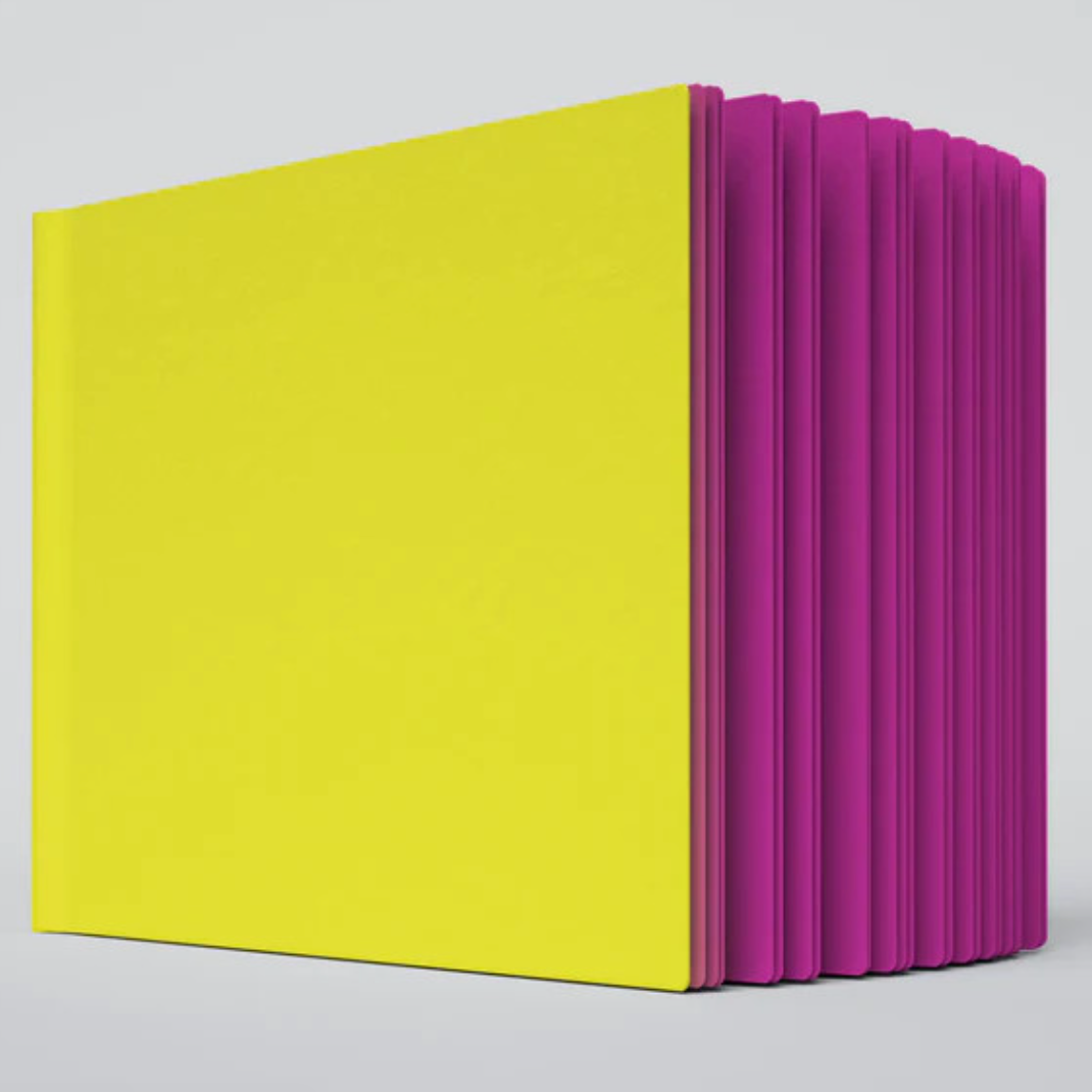 A close up photo of the Razzle Dazzle ugly book sketchbook. The cover is bright yellow and the pages are hot pink colored.