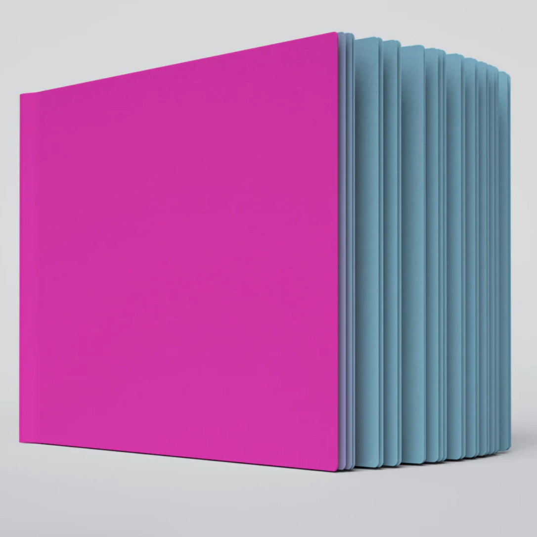 A close up photo of the sprinkles ugly book sketchbook. The cover is bright pink and the pages are teal colored.