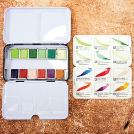Set of watercolor paints in a portable case on a cork background. 