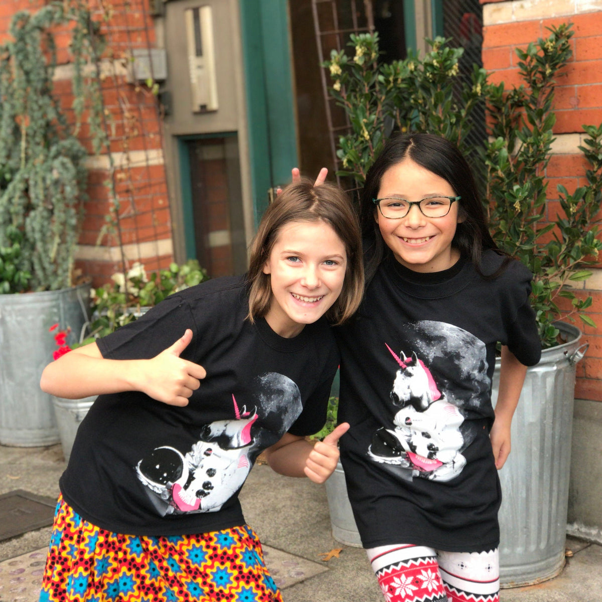 Two youths dressed in matching black Astronaut Unicorn tshirts.