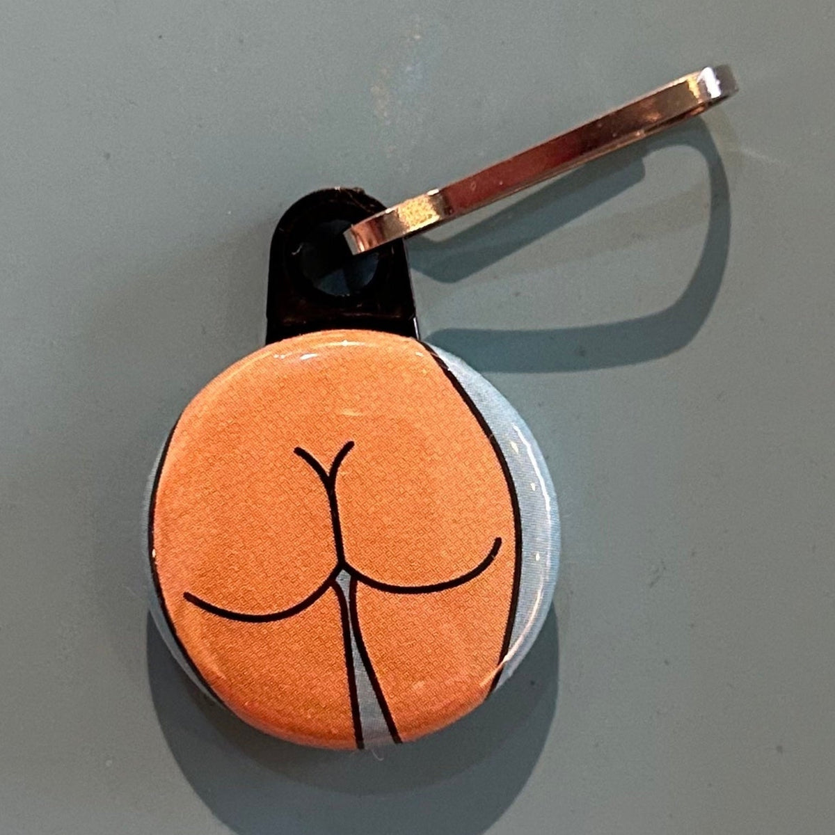 Small zipper pull with a round butt against a gray background. 