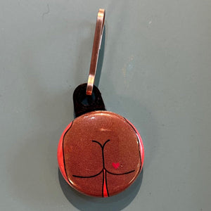 Zipper pull with a square butt design on a gray background. 