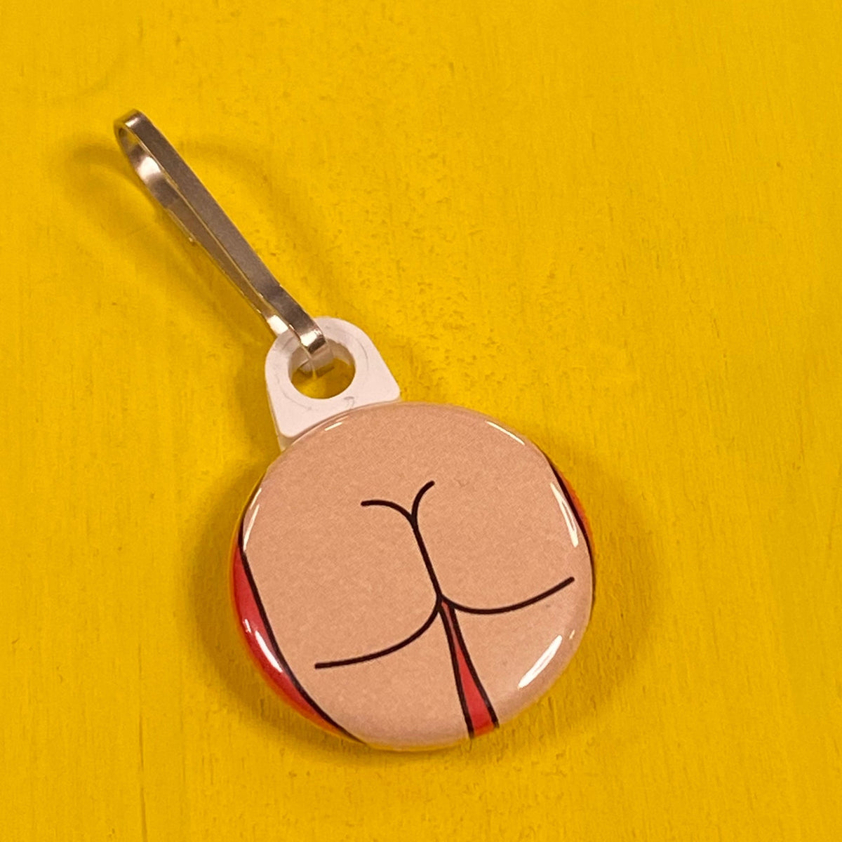Zipper pull with a square butt design on a yellow surface. 
