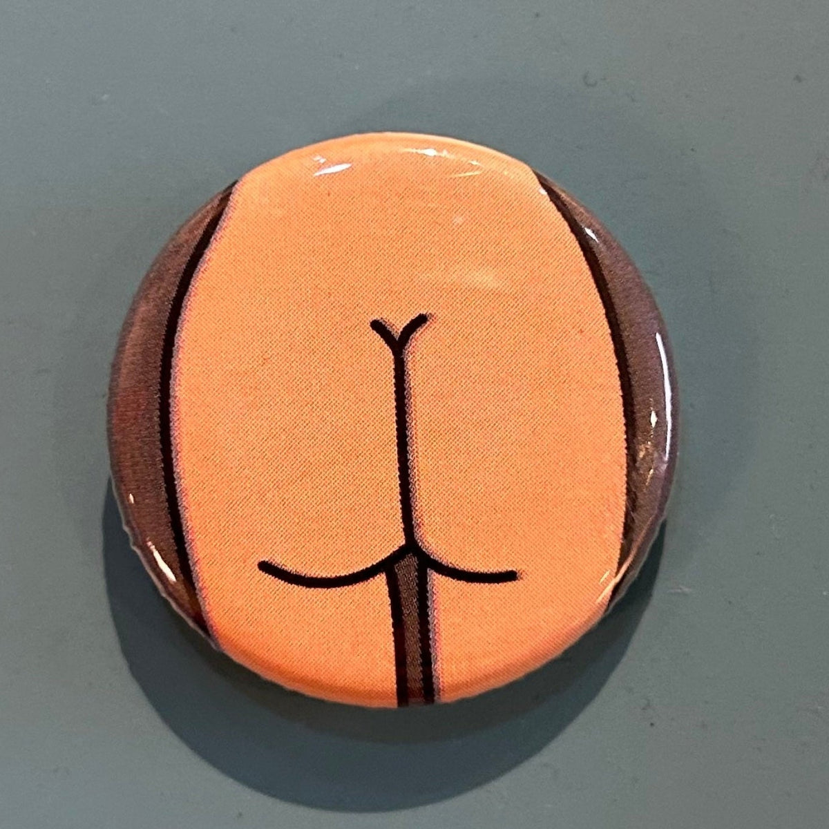 Round zipper pull with a thin butt design against a gray background. 