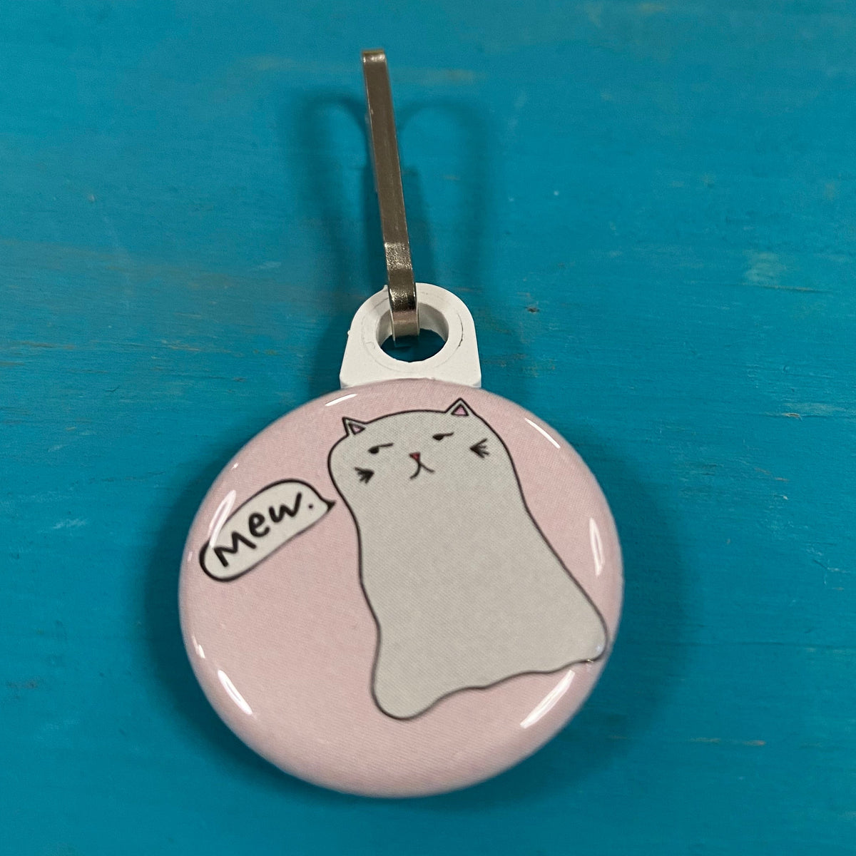 Keychain with a Ghost Kitty illustration on a blue and yellow surface. 
