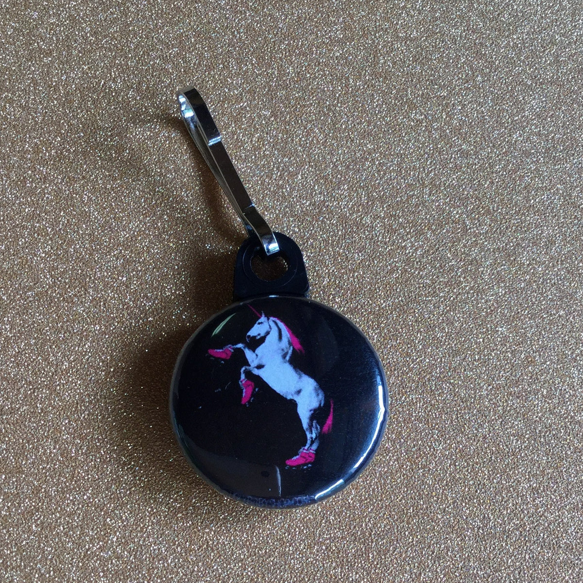 A zipper pull with a roller skating unicorn on a black background.