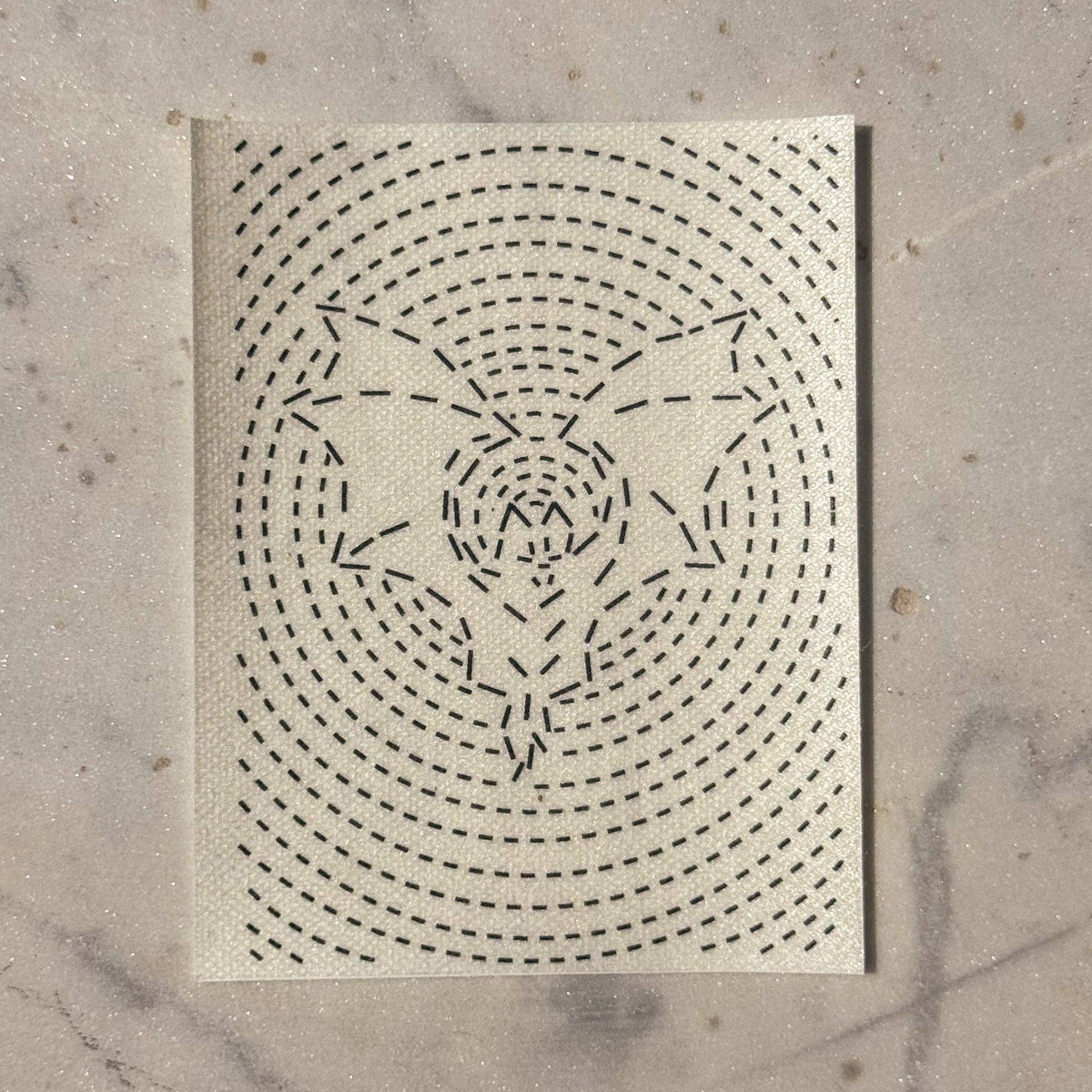 A visible mending patch of a bat in flight surrounded by concentric circles on a marble background. 