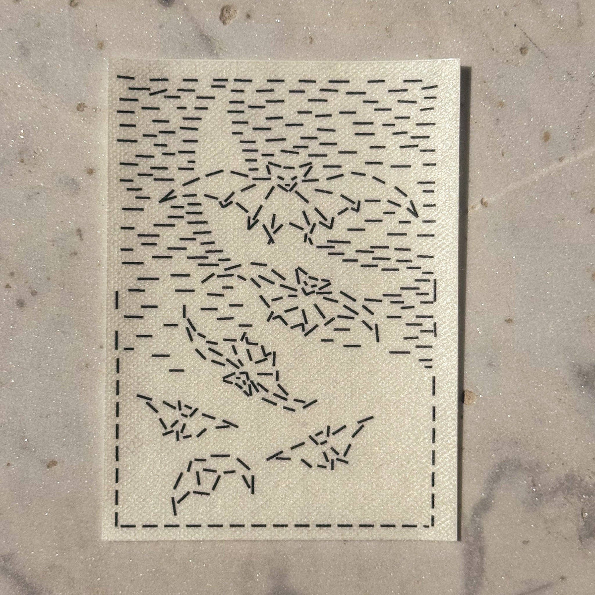 A visible mending guide sticker featuring a design of six bats and hatched lines that create the silhouette of a crescent moon. 