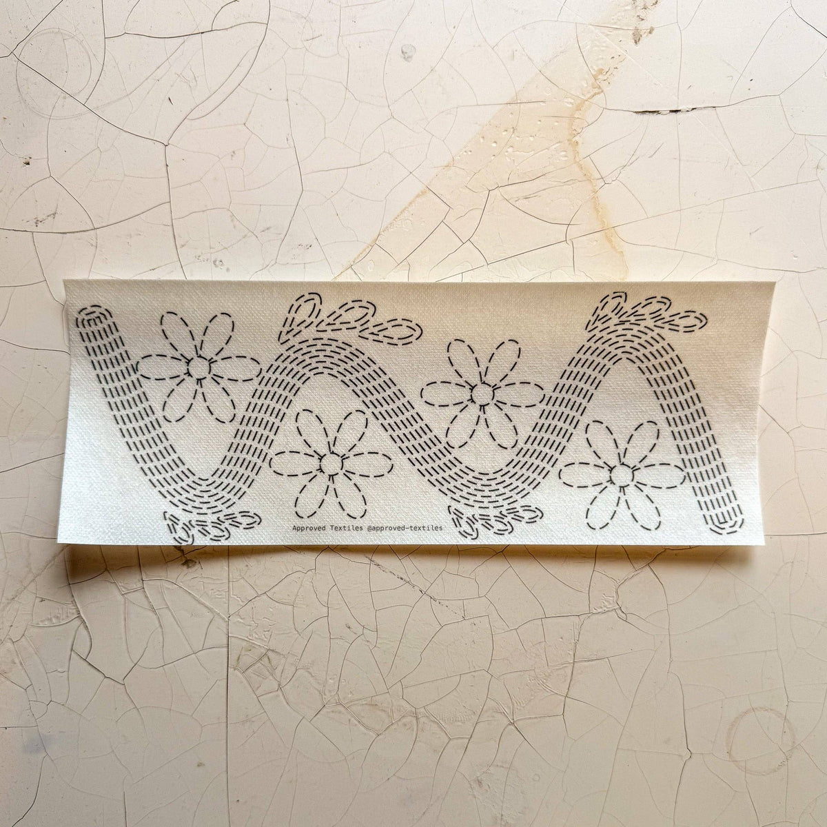 Visible mending guide sticker featuring four daisies and a wavy line with leaves on each bump. 