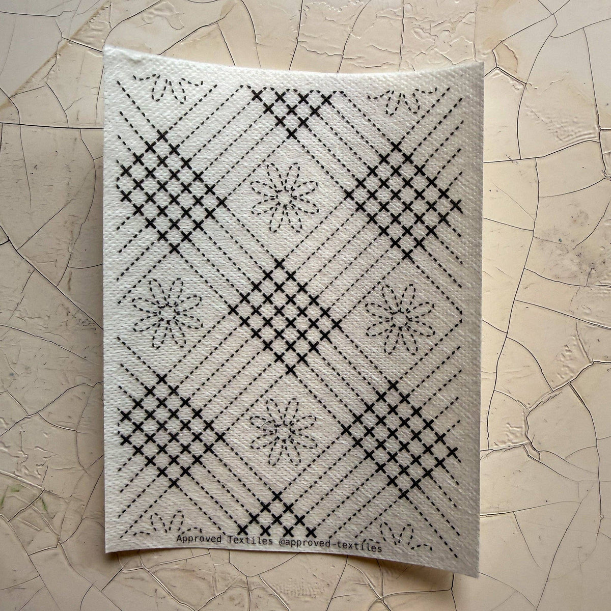 Visible mending guide sticker featuring a plaid-like grid pattern and daisies. 