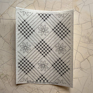 Visible mending guide sticker featuring a plaid-like grid pattern and daisies. 