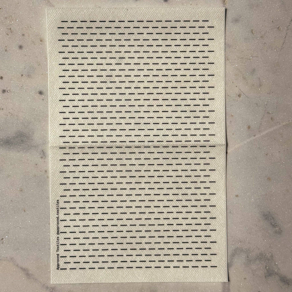 Visible mending guide sticker of many rows of horizontal lines against a marble background. 
