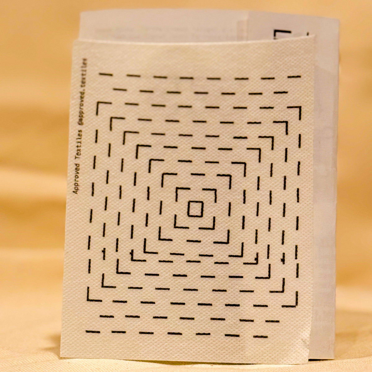 Visible mending guides sticker featuring concentric squares against a light yellow out-of-focus background. 
