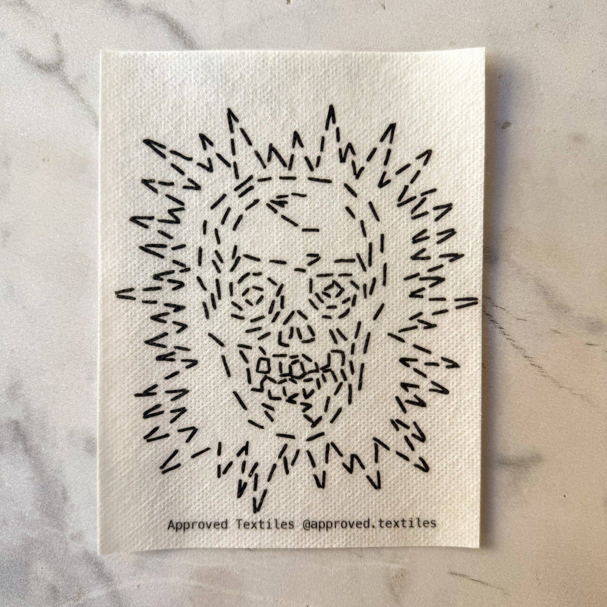 Visible mending pattern sticker featuring a skull surrounded by a sunburst pattern 