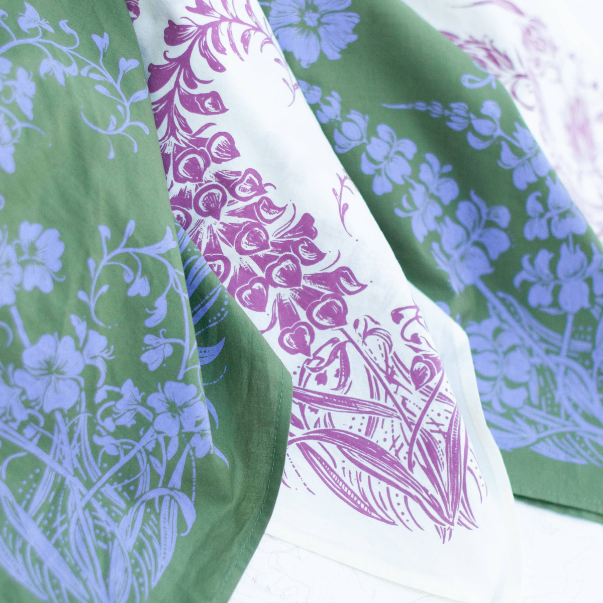 Set of floral-patterned green and purple bandanas on a white background. 