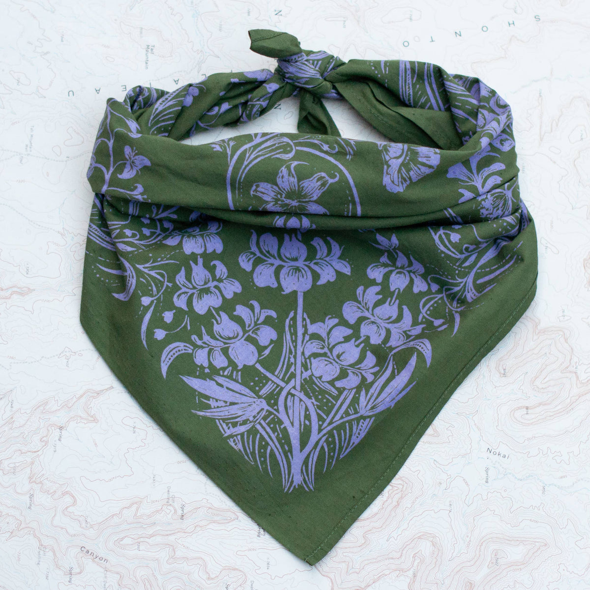 Green bandana with purple floral pattern on a textured white background
