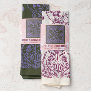 Two patterned bandanas in green & lavender and pink & white on a textured white background. 