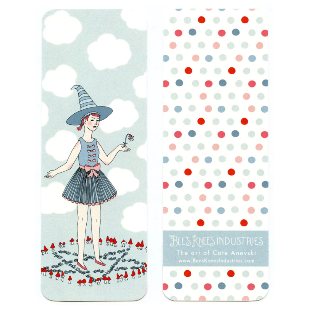 A bookmark that has a witch wearing a blue dress and hat standing in a fairy ring on one side and multicolor polka dots against a white background on the other. 