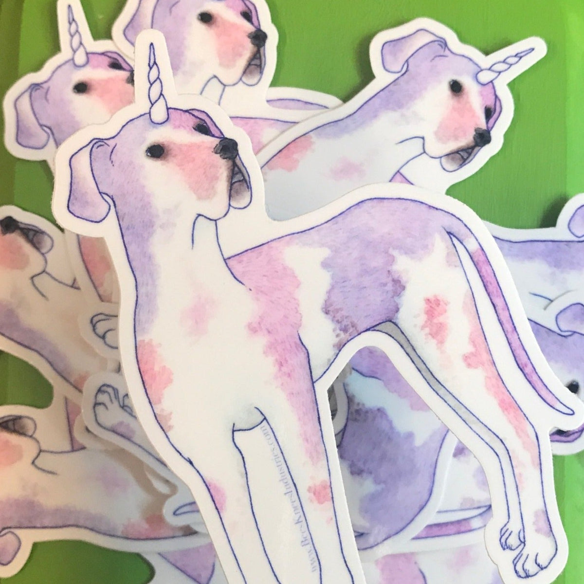 A sticker of a pink and purple Great Dane with a unicorn horn.