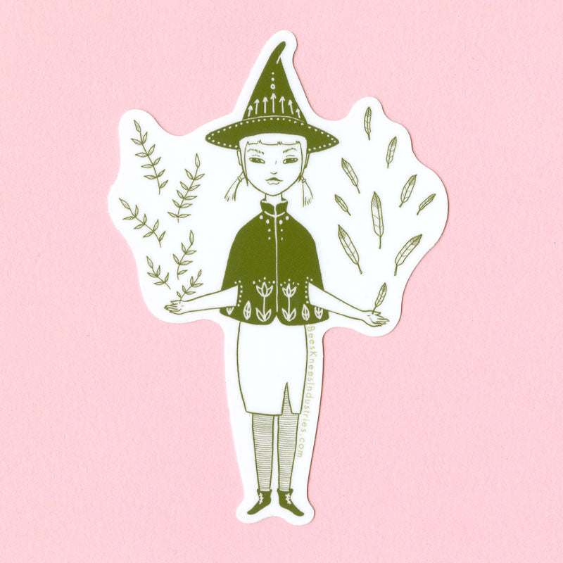 A sticker illustrated in green of a witch wearing a skirt, small cape, and pointy hat with feathers flying out of her left hand and leaves flying out of her right. 