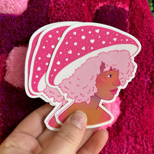 Three die-cut stickers featuring a stylized illustration of a woman with pink hair and a pink hat with white hearts shaped like a mushroom, held in a hand against a textured magenta background.