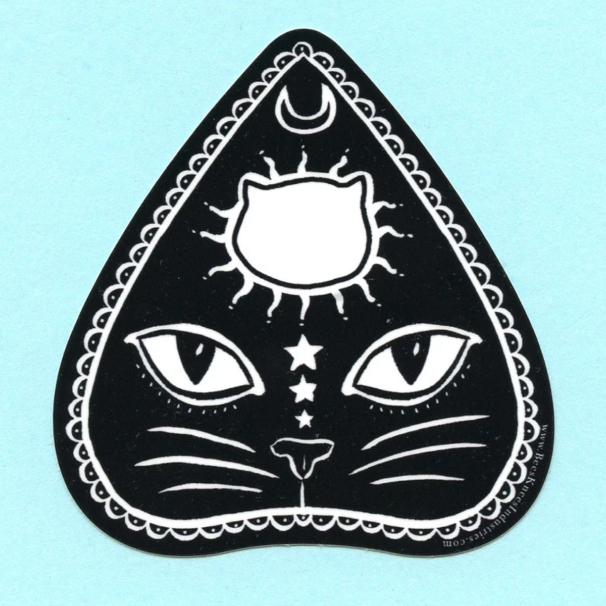 Sticker of a planchette with a cat's face on it against a light blue background. 