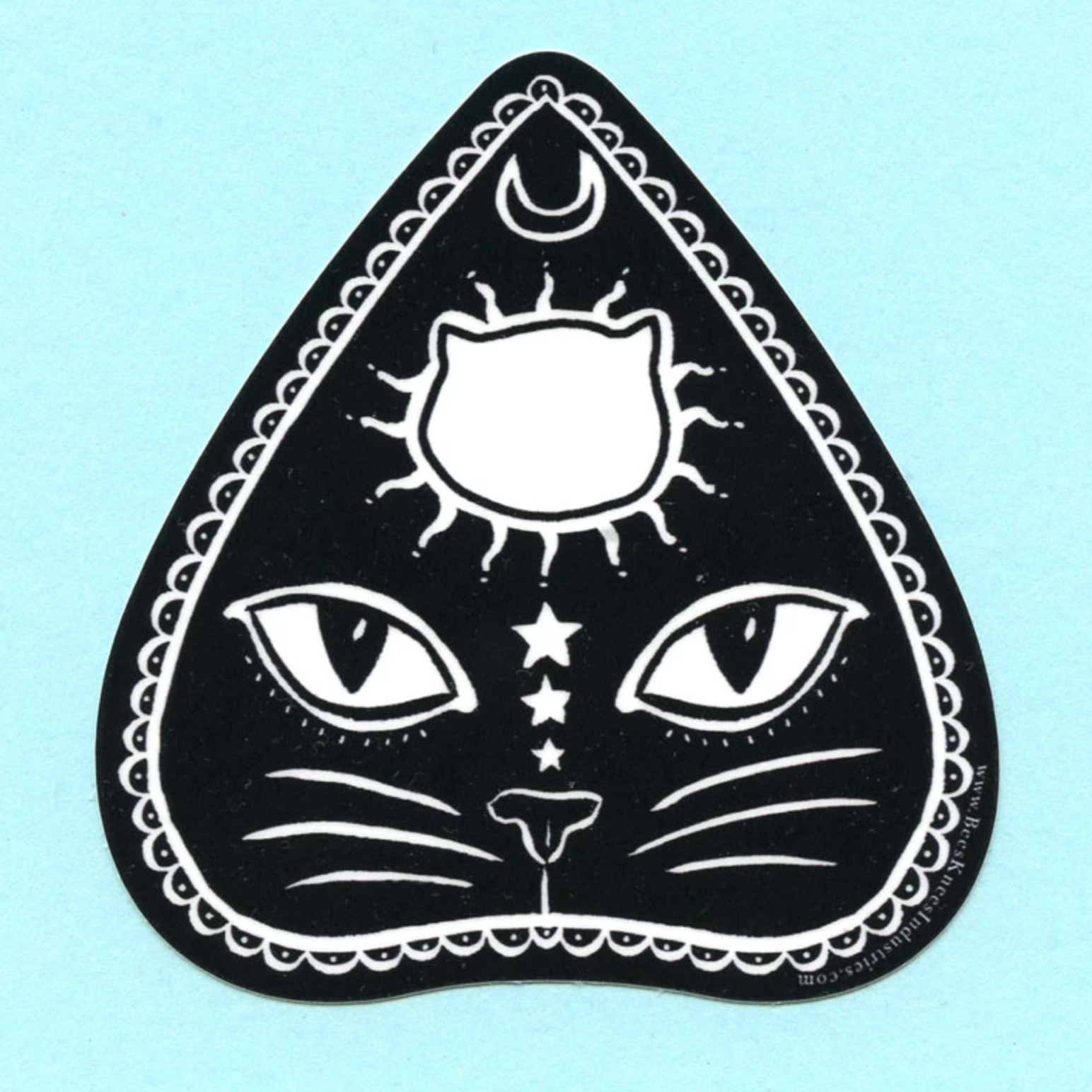Sticker of a planchette with a cat's face on it against a light blue background. 