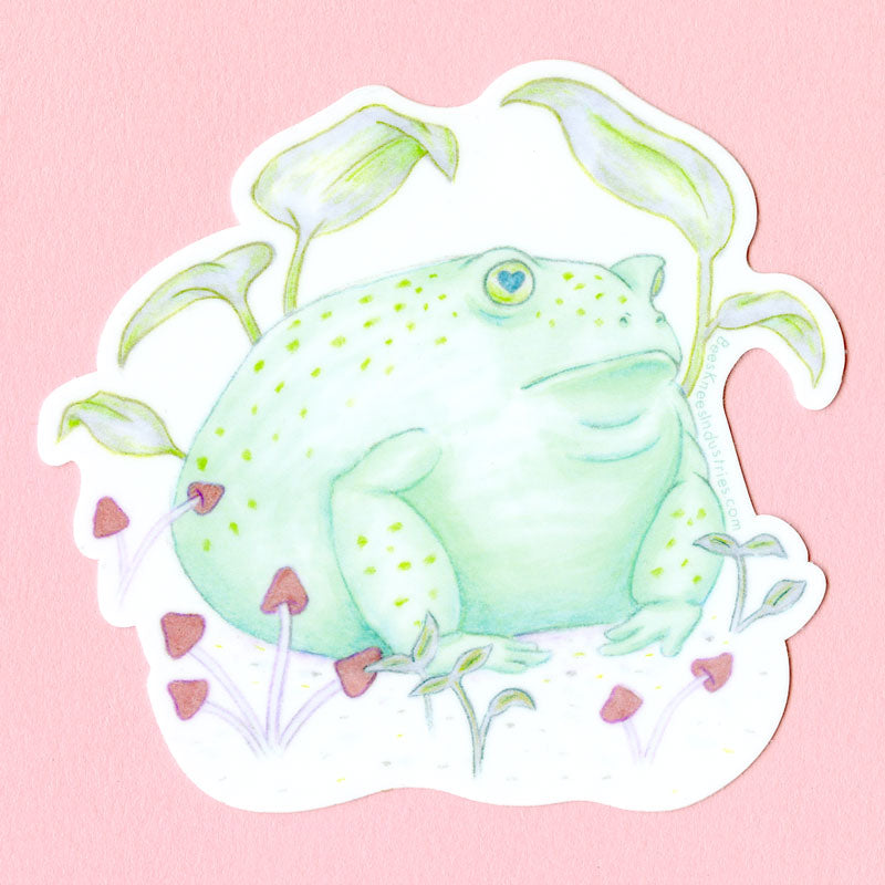 A sticker of a round toad sitting in a field of mushrooms and sprouts. 