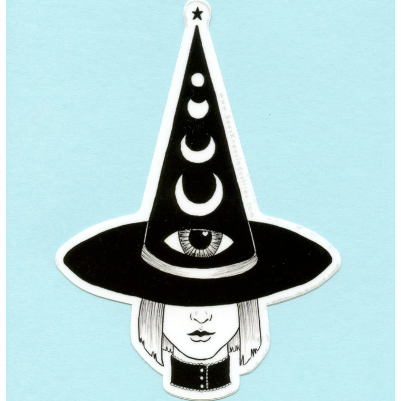 Black and white sticker of a witch with a bob haircut wearing a pointy hat that has an eye on it and different phases of the moon. 