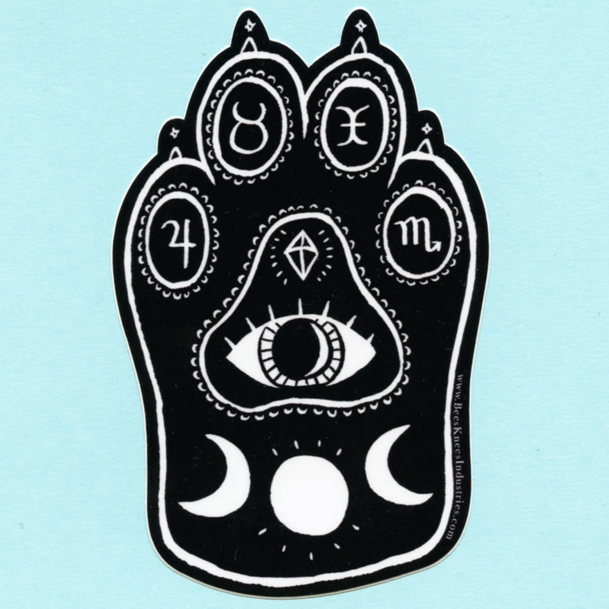 Black and white sticker of a cat's paw with sun and moons, an eye, and zodiac signs on the toe pads. 