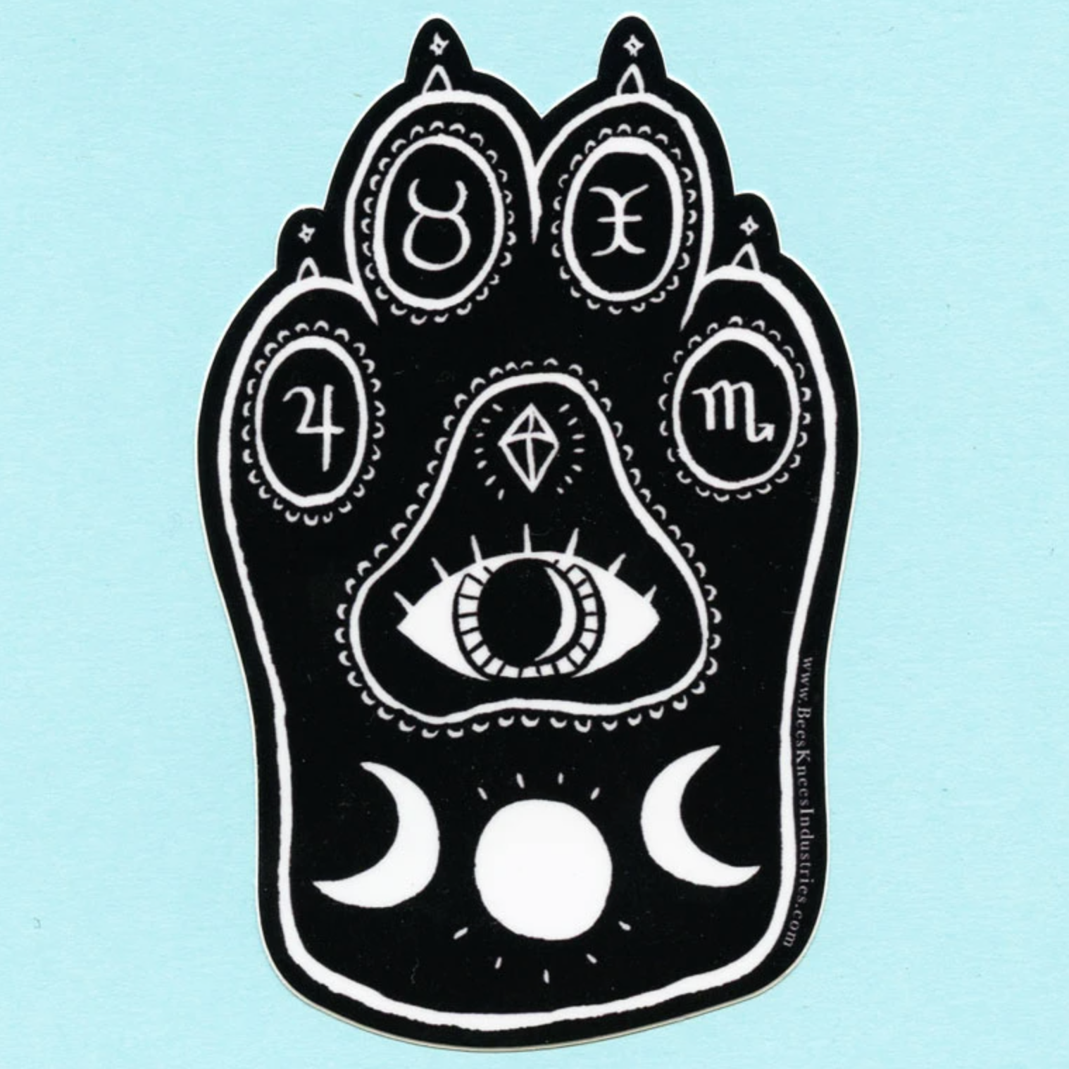 Black and white sticker of a cat's paw with sun and moons, an eye, and zodiac signs on the toe pads. 