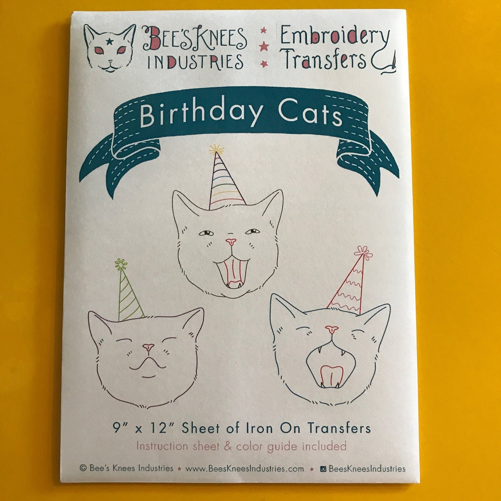 A white envelope that says "Bee's Knees Industries Embroidery Transfers: Birthday Cats" and has illustrations of three cats wearing party hats against a yellow background.