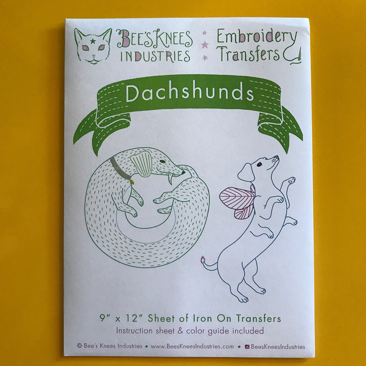 A white envelope that says "Bee's Knees Industries Embroidery Transfers: Dachshunds" and has two illustrations of dachshunds against a yellow background.