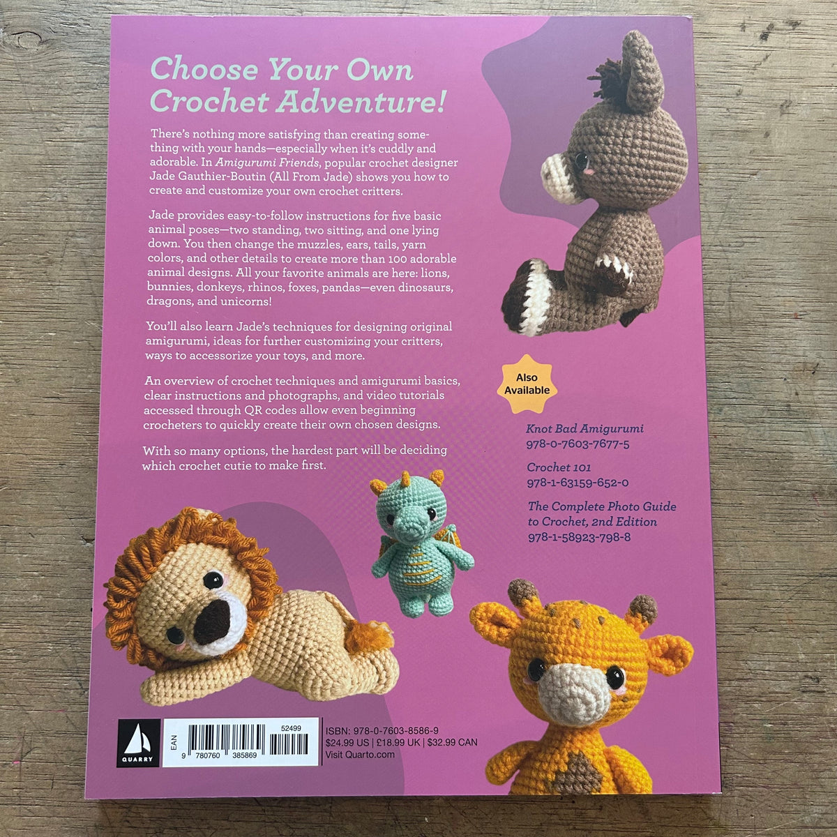 Back cover of a crochet guide book titled 'Choose Your Own Crochet Adventure!' on a pink background, showing several crocheted animal designs and product details for 'Knot Ball Amigurumi' and 'Crochet 101'.